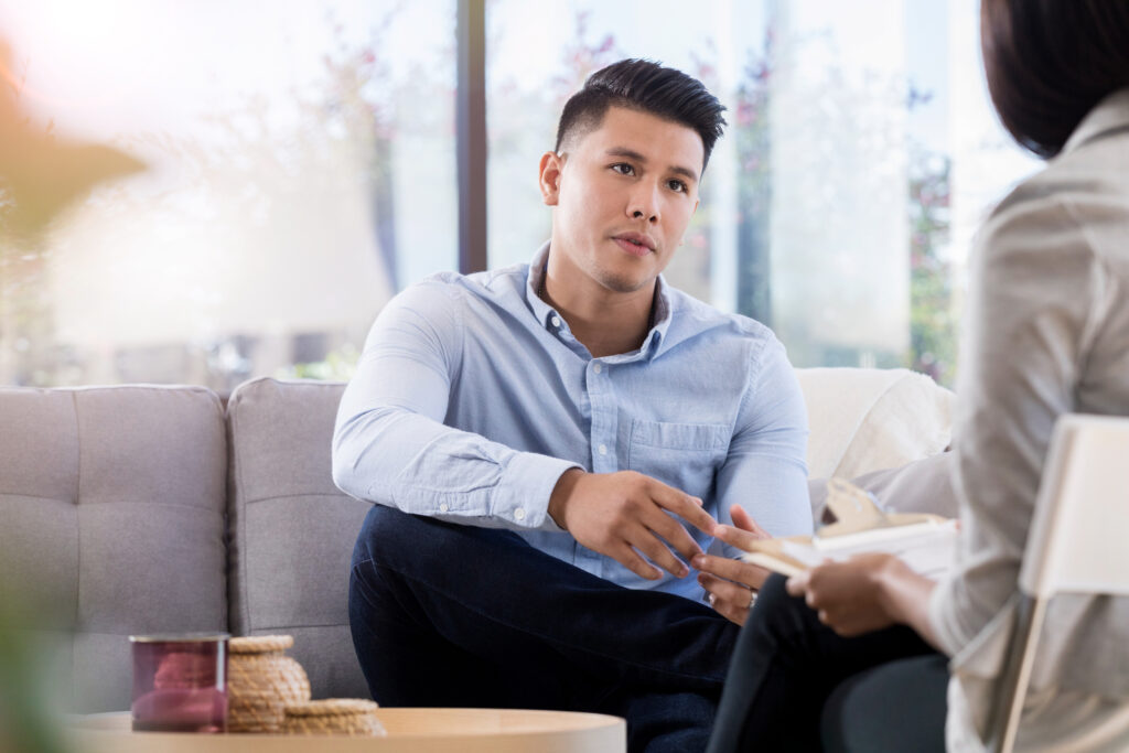 young male participating in cognitive behavioral therapy while talking to psychiatrist or therapist